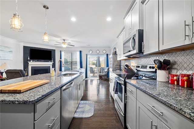 kitchen featuring a center island with sink, appliances with stainless steel finishes, sink, backsplash, and dark hardwood / wood-style flooring