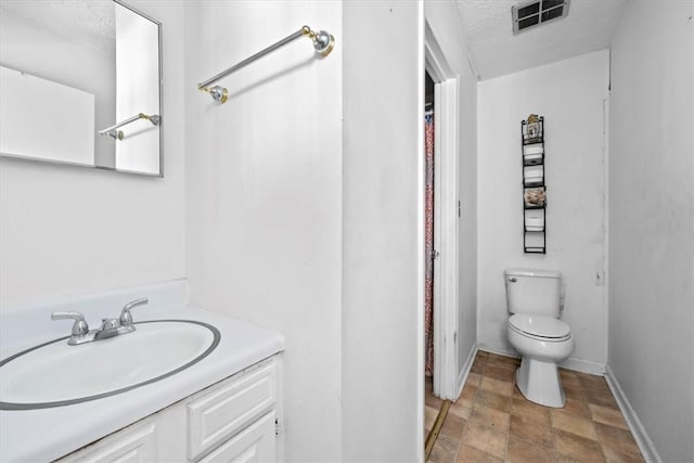 bathroom featuring a textured ceiling, toilet, and vanity