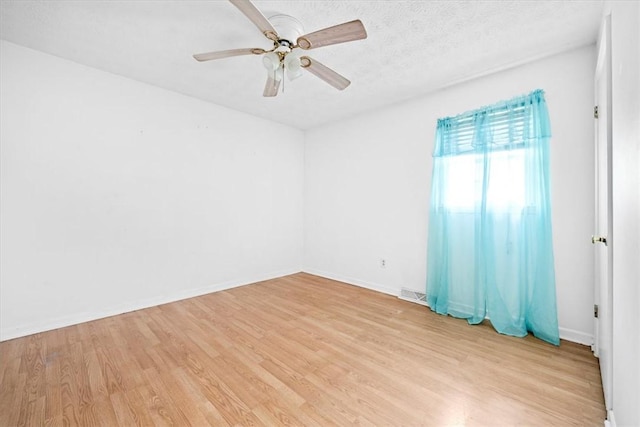 unfurnished room with ceiling fan, light wood-type flooring, and a textured ceiling