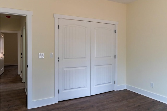 unfurnished bedroom with dark hardwood / wood-style flooring and a closet