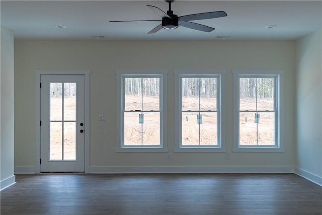 doorway with a healthy amount of sunlight, ceiling fan, and dark hardwood / wood-style floors