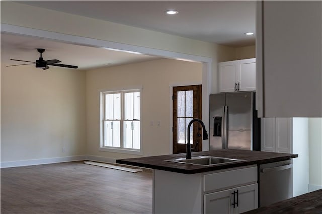 kitchen with appliances with stainless steel finishes, wood-type flooring, sink, white cabinetry, and ceiling fan