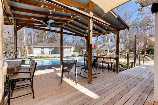 wooden terrace with an outdoor bar, ceiling fan, and an outdoor structure