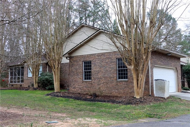 view of side of property with a garage, a yard, brick siding, and crawl space