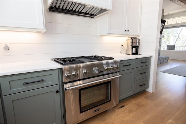 kitchen featuring white cabinets, light wood-type flooring, custom range hood, and high end range