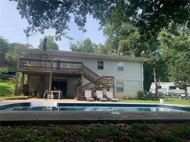 back of house with a wooden deck, fence, stairs, and an outdoor pool
