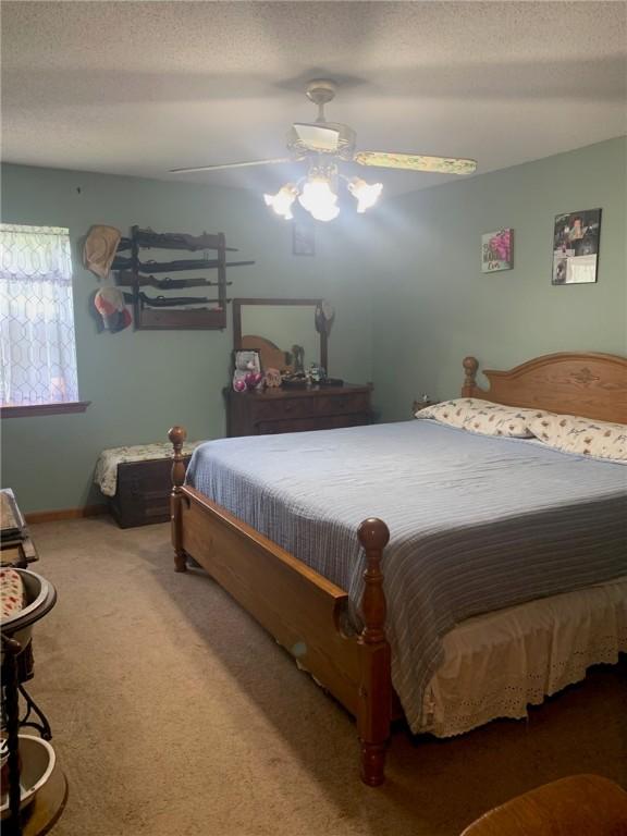carpeted bedroom with baseboards, a ceiling fan, and a textured ceiling