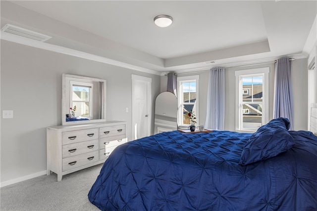 bedroom with multiple windows, crown molding, light colored carpet, and a raised ceiling