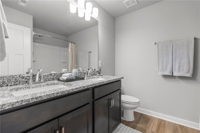 bathroom with toilet, vanity, wood-type flooring, and walk in shower