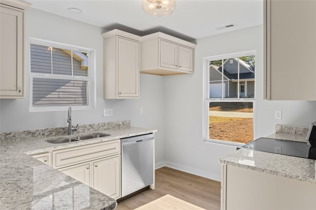 kitchen with stainless steel dishwasher, light hardwood / wood-style flooring, sink, and light stone countertops