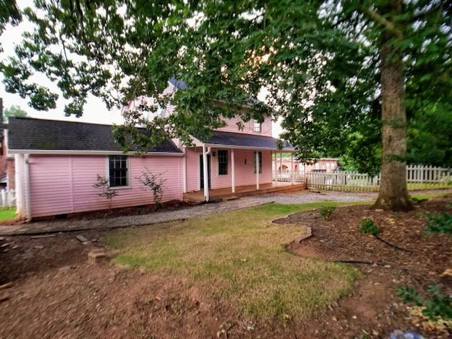 rear view of property featuring a yard and a porch