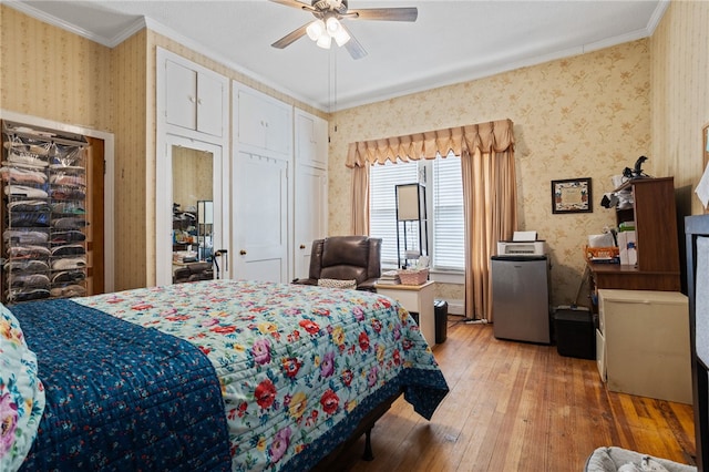 bedroom featuring ceiling fan, light hardwood / wood-style flooring, crown molding, and stainless steel refrigerator