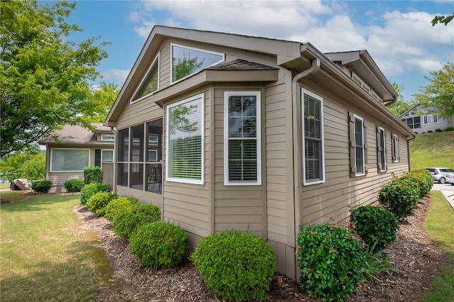 view of side of home featuring a sunroom and a yard