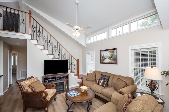 living room with a high ceiling, ceiling fan, and hardwood / wood-style flooring