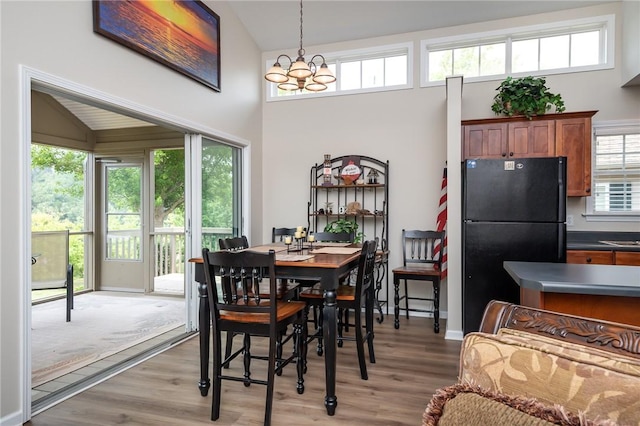 dining area featuring high vaulted ceiling, an inviting chandelier, and light hardwood / wood-style flooring