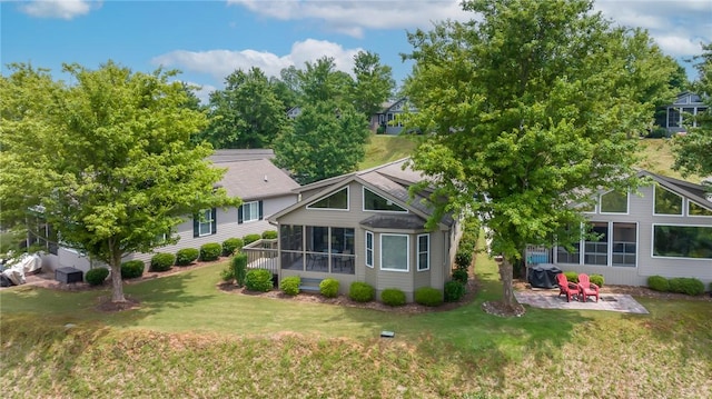 rear view of property with a sunroom, a yard, and a patio