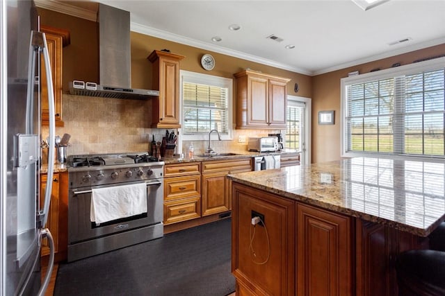 kitchen featuring visible vents, wall chimney exhaust hood, appliances with stainless steel finishes, light stone countertops, and a sink