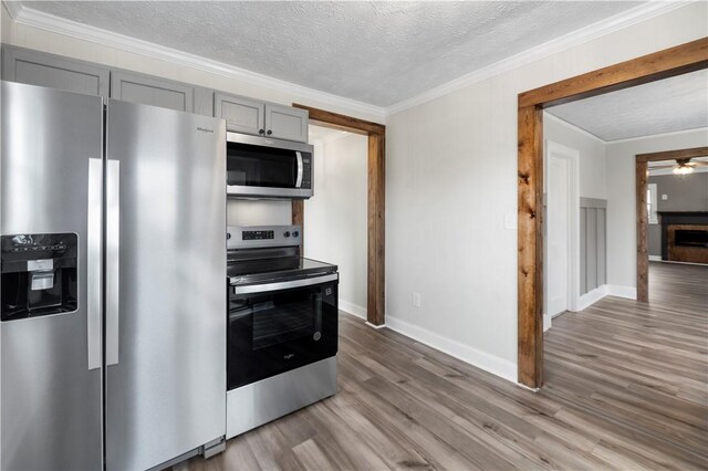 kitchen featuring a textured ceiling, appliances with stainless steel finishes, gray cabinets, and light wood-style floors