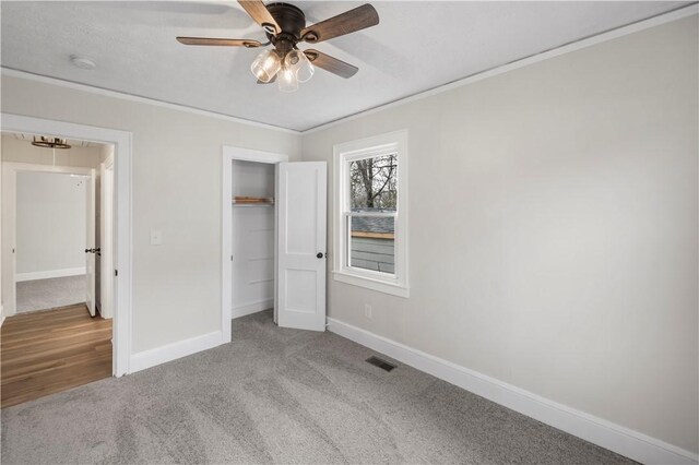 unfurnished bedroom featuring attic access, visible vents, baseboards, ornamental molding, and carpet