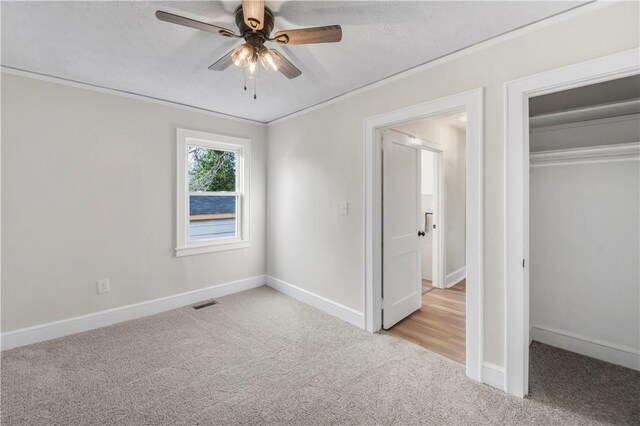 unfurnished bedroom featuring baseboards, crown molding, a closet, and light colored carpet