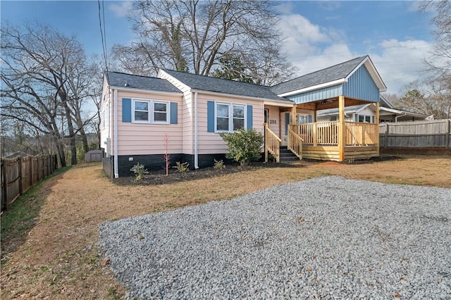 view of front of home with a porch, roof with shingles, and fence