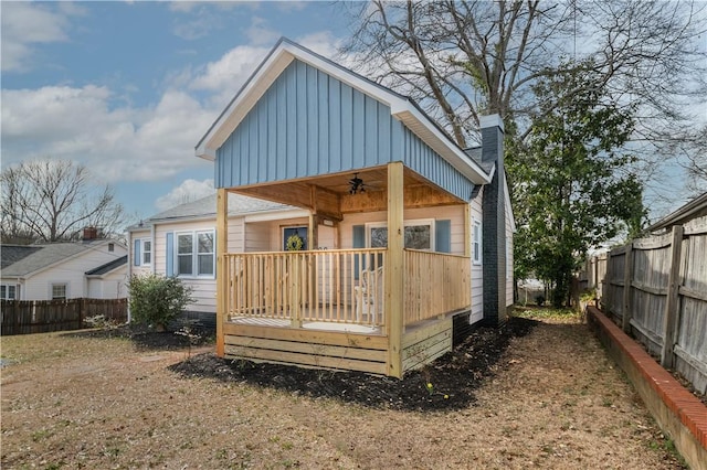 rear view of property with a ceiling fan, covered porch, a fenced backyard, and board and batten siding