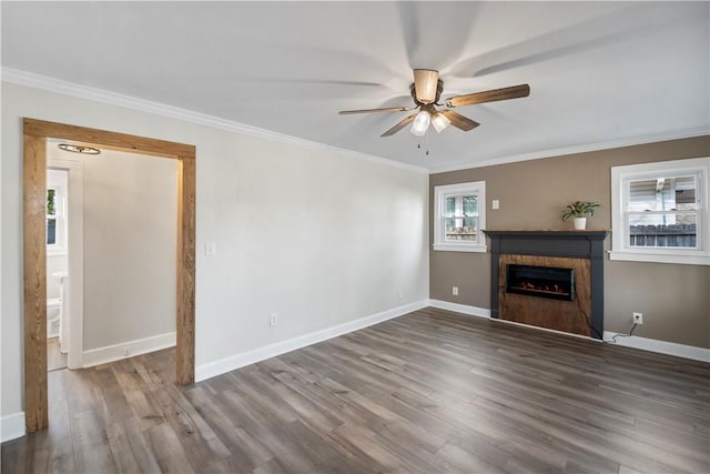 unfurnished living room featuring ornamental molding, a fireplace, baseboards, and wood finished floors