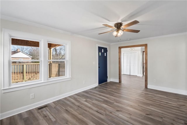 empty room with dark wood finished floors, visible vents, ornamental molding, ceiling fan, and baseboards