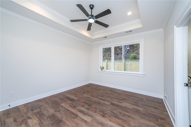 spare room with baseboards, visible vents, a raised ceiling, dark wood-style floors, and crown molding