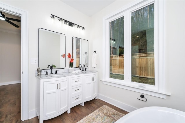 bathroom featuring double vanity, wood finished floors, a sink, and baseboards