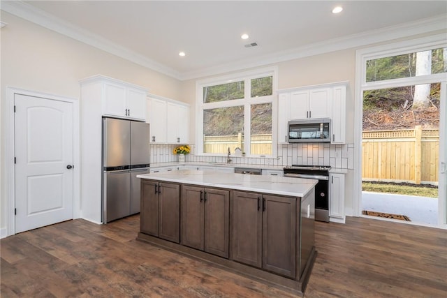 kitchen with white cabinetry, appliances with stainless steel finishes, a wealth of natural light, and a center island