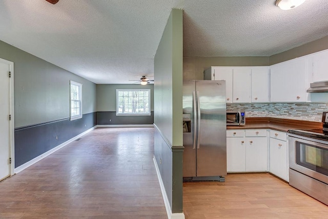 kitchen with under cabinet range hood, a ceiling fan, white cabinetry, appliances with stainless steel finishes, and light wood-type flooring