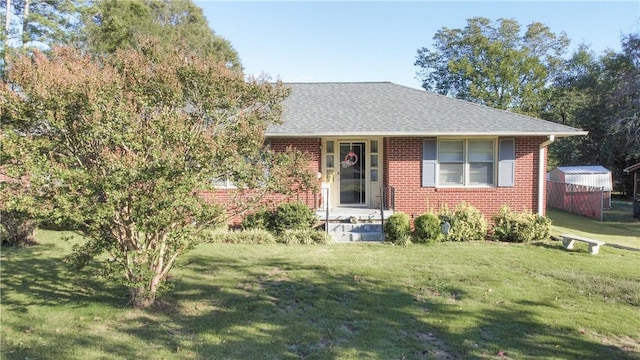 view of front of home featuring brick siding, a shingled roof, and a front yard