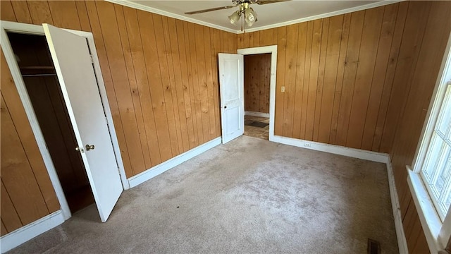 unfurnished bedroom with crown molding, carpet floors, visible vents, and wooden walls