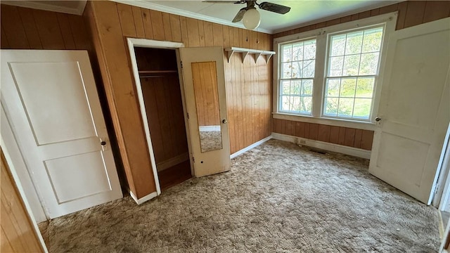 unfurnished bedroom with light carpet, crown molding, baseboards, and wooden walls