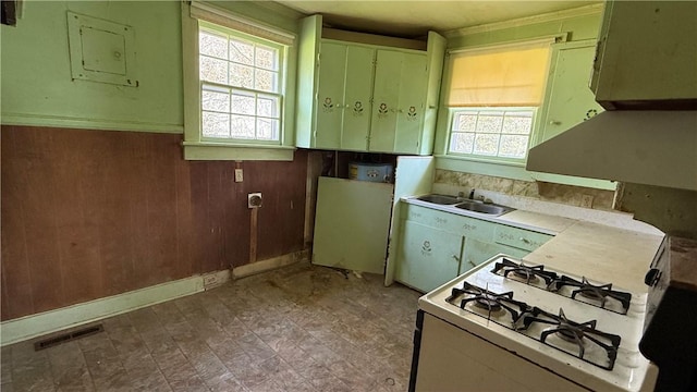 kitchen with wood walls, a sink, visible vents, light countertops, and gas range gas stove