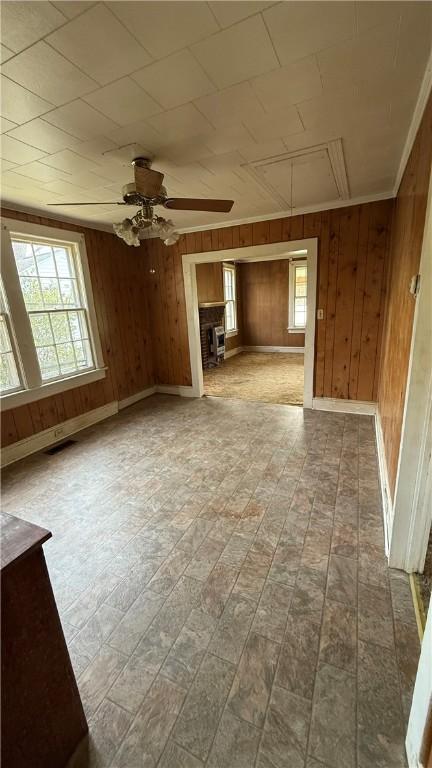 unfurnished living room with attic access, a wealth of natural light, and baseboards