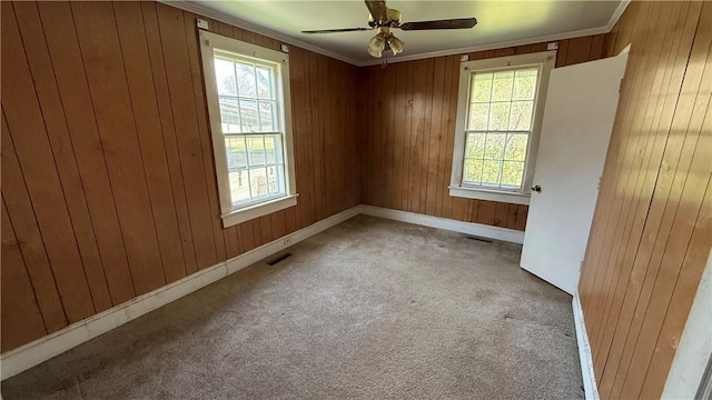 carpeted empty room featuring ornamental molding, visible vents, and wooden walls