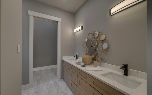 bathroom with double vanity, marble finish floor, baseboards, and a sink