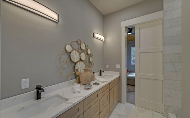 ensuite bathroom featuring double vanity, connected bathroom, and a sink