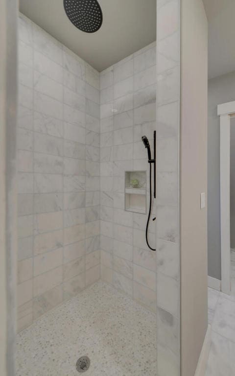 full bath featuring baseboards and a tile shower