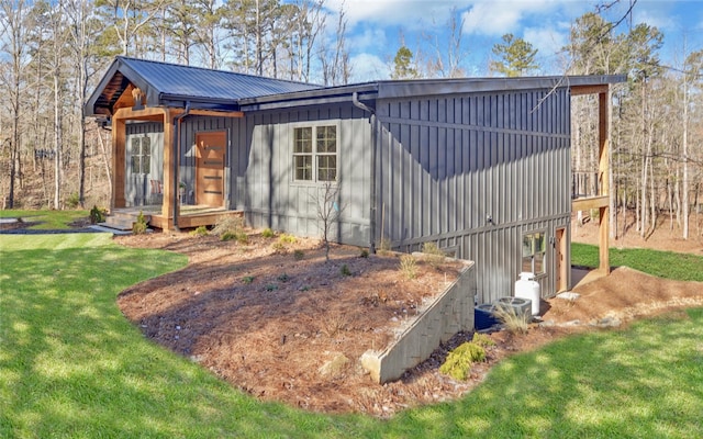 view of front facade with board and batten siding, metal roof, and a front lawn