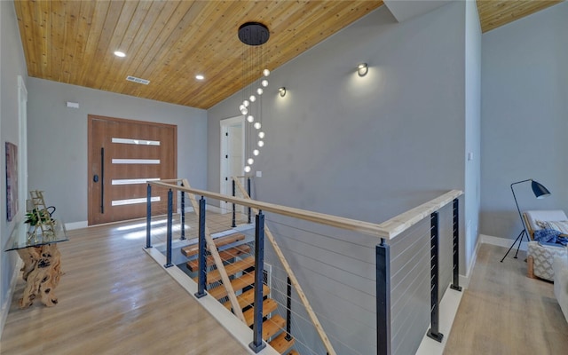 corridor featuring wooden ceiling, light wood-style flooring, visible vents, and an upstairs landing