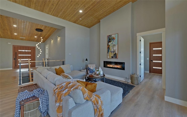 living area with light wood-type flooring, a glass covered fireplace, wooden ceiling, and recessed lighting