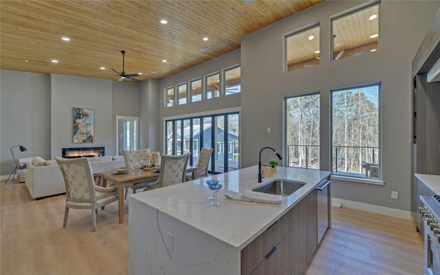 kitchen with wooden ceiling, a sink, open floor plan, modern cabinets, and a glass covered fireplace