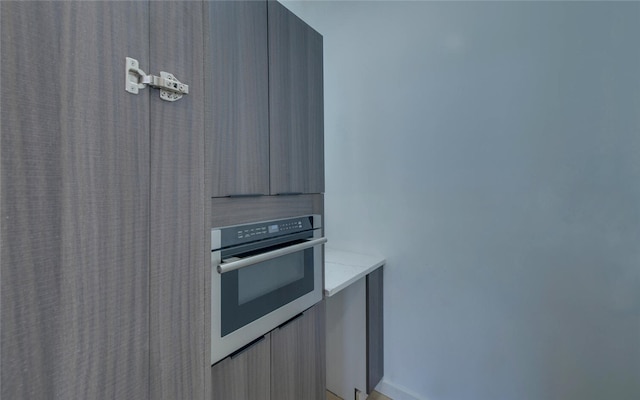 kitchen with light brown cabinetry, light countertops, stainless steel oven, and modern cabinets