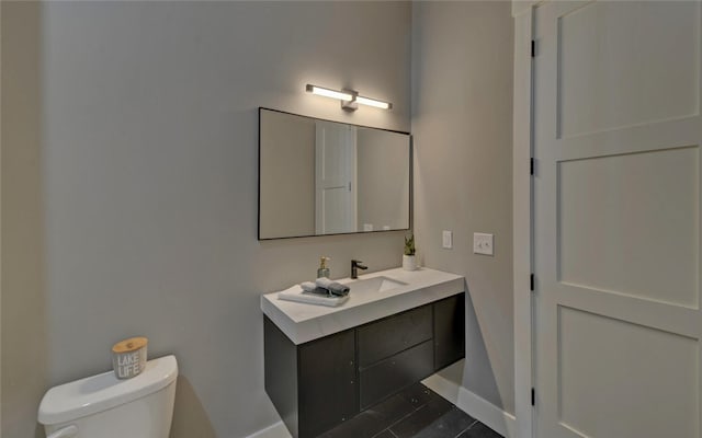 bathroom with baseboards, vanity, and toilet