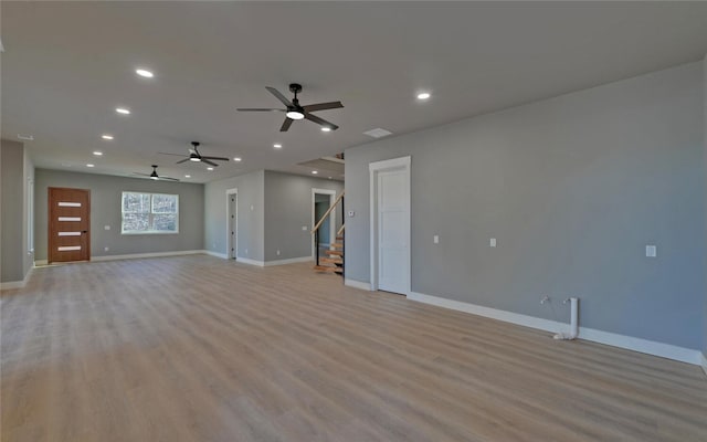 unfurnished living room with light wood finished floors, stairway, baseboards, and recessed lighting