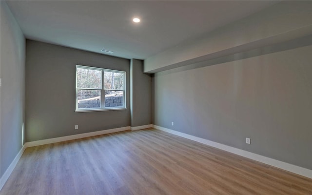 spare room featuring light wood-style floors, recessed lighting, and baseboards