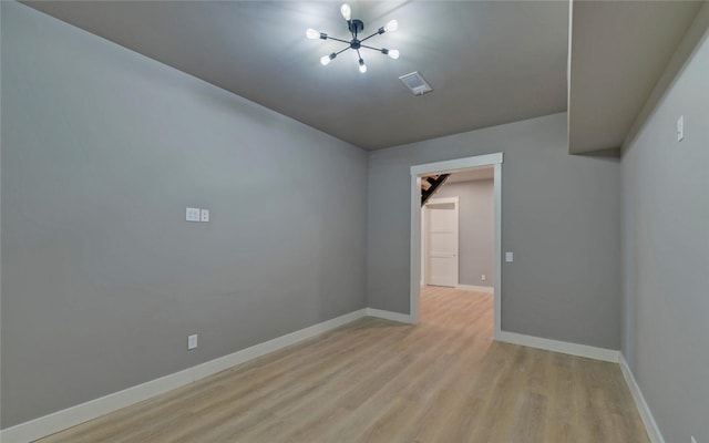 spare room with light wood-type flooring, visible vents, and baseboards